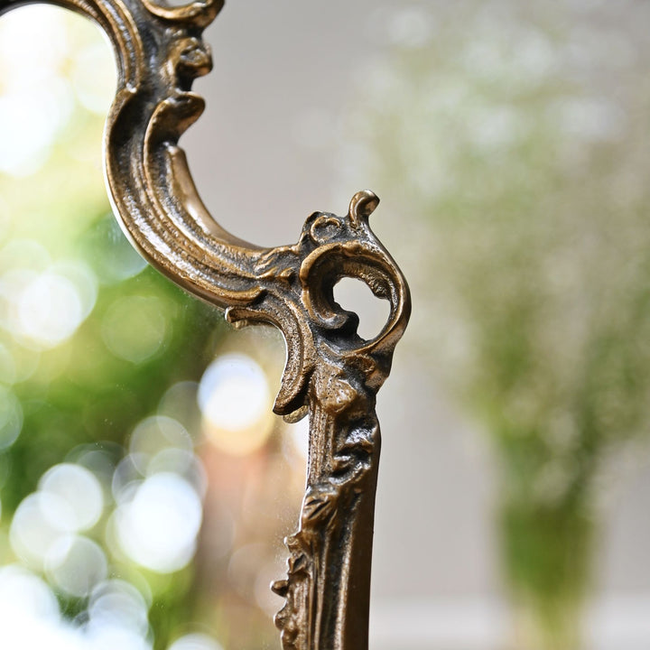Baroque-style ornate tabletop mirror with an antique gold frame and sculpted detailing.