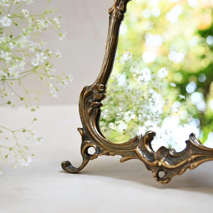 Baroque-style ornate tabletop mirror with an antique gold frame and sculpted detailing.