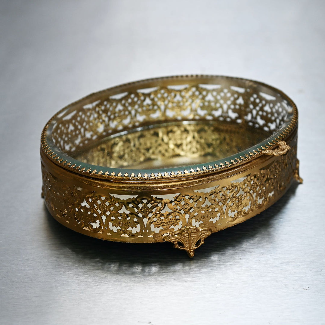 Large brass oval box with glass lid and  intricate brass detailing.