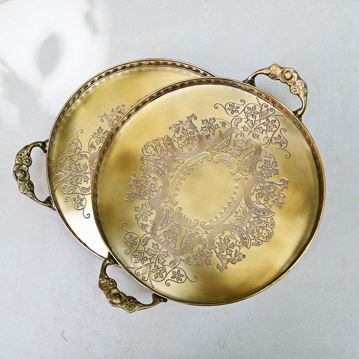 Gold decorative trays with intricate patterns on a light gray background