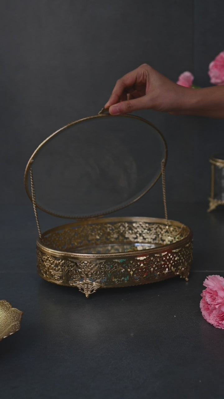 Large brass oval box with glass lid and  intricate brass detailing.