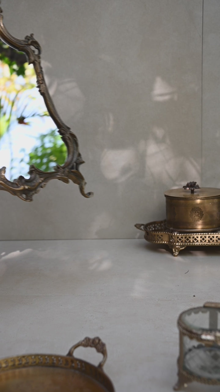 Baroque-style ornate tabletop mirror with an antique gold frame and sculpted detailing.