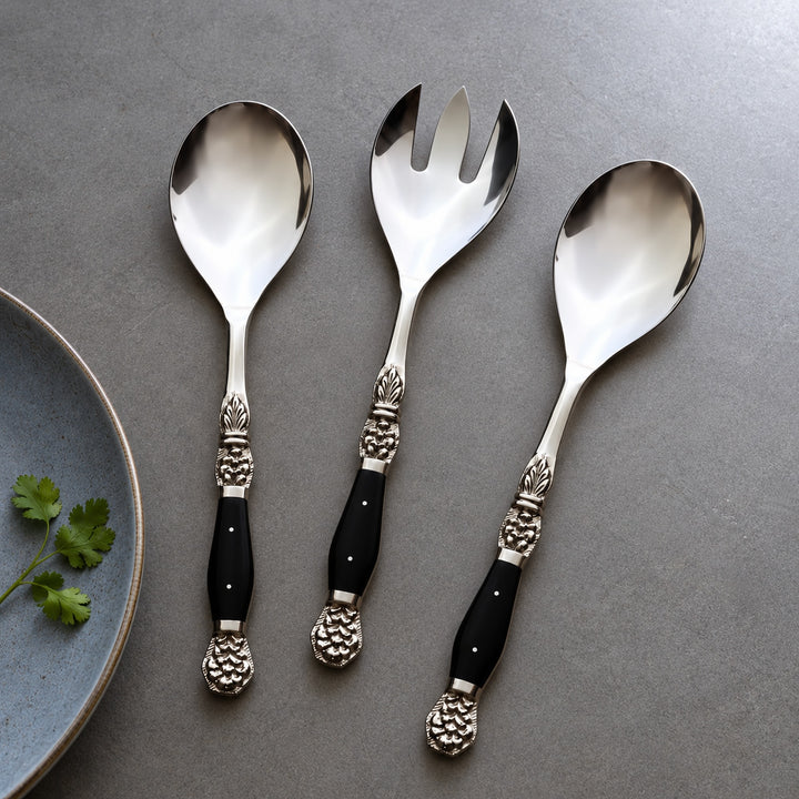 Two Windsor serving spoons and one serving fork styled beside a blue plate and coriander.