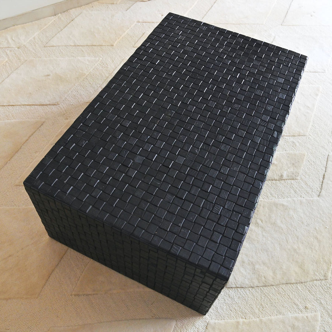 Black woven rectangular coffee table on a light wood floor