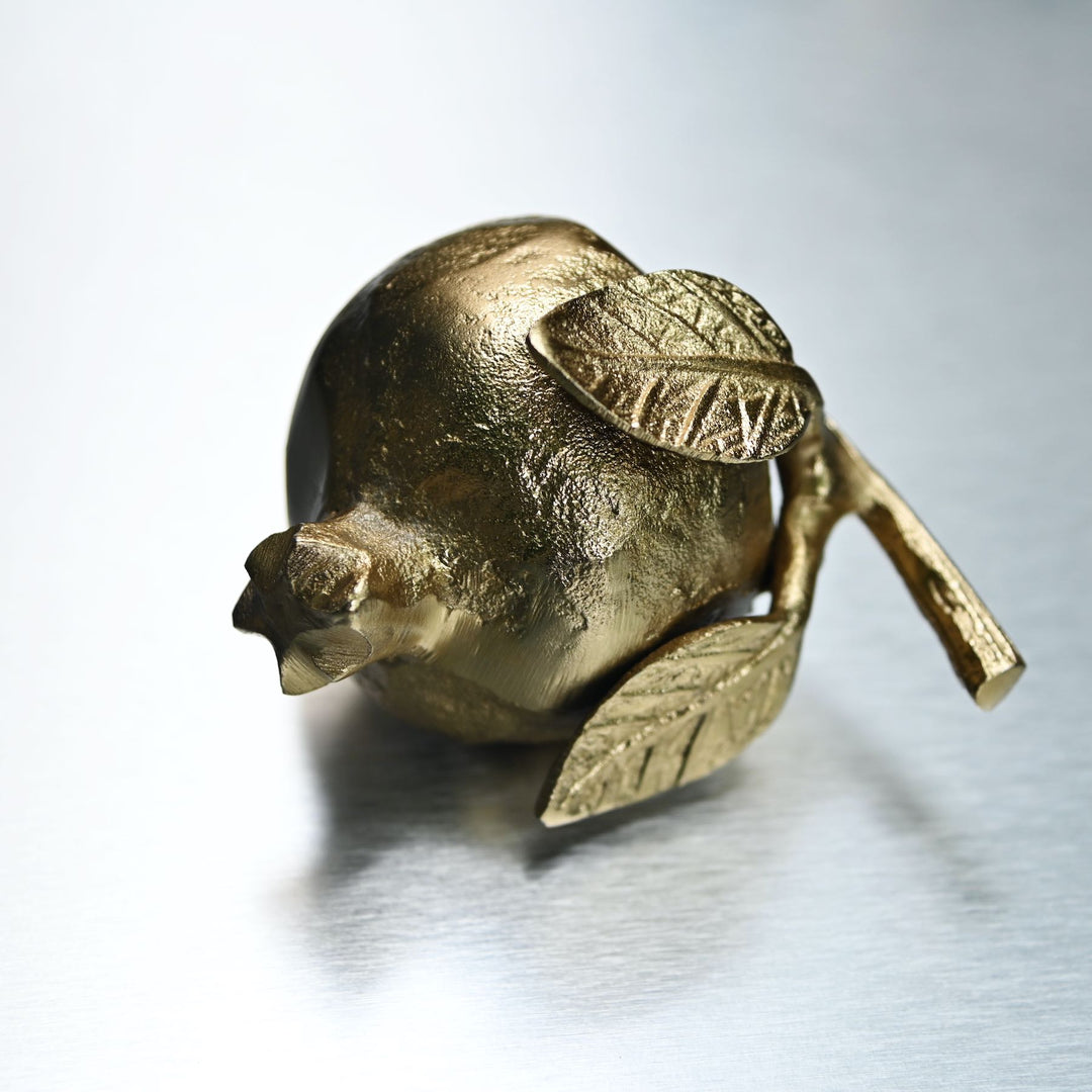 Gold pomegranate figurine with leaves on a white background