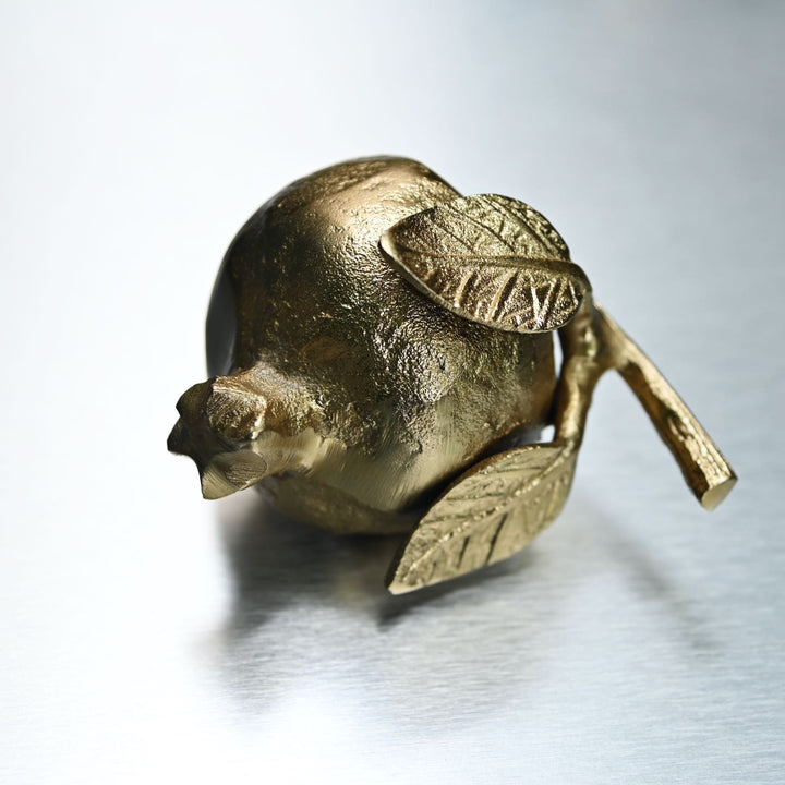 Gold pomegranate figurine with leaves on a white background