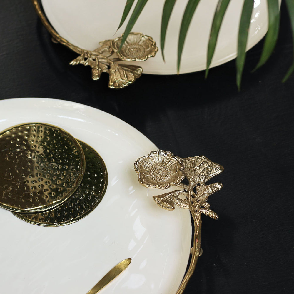 Close-up of the golden flower on a white tray with gold-tone coasters nearby