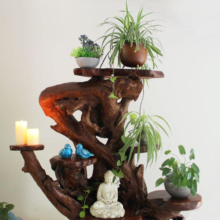 Wooden plant stand with potted plants, candles, and a Buddha statue on a plain background