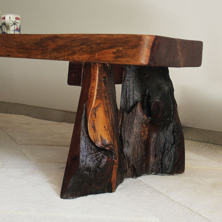 Teak wood bench with natural, rustic design on a light-colored floor.