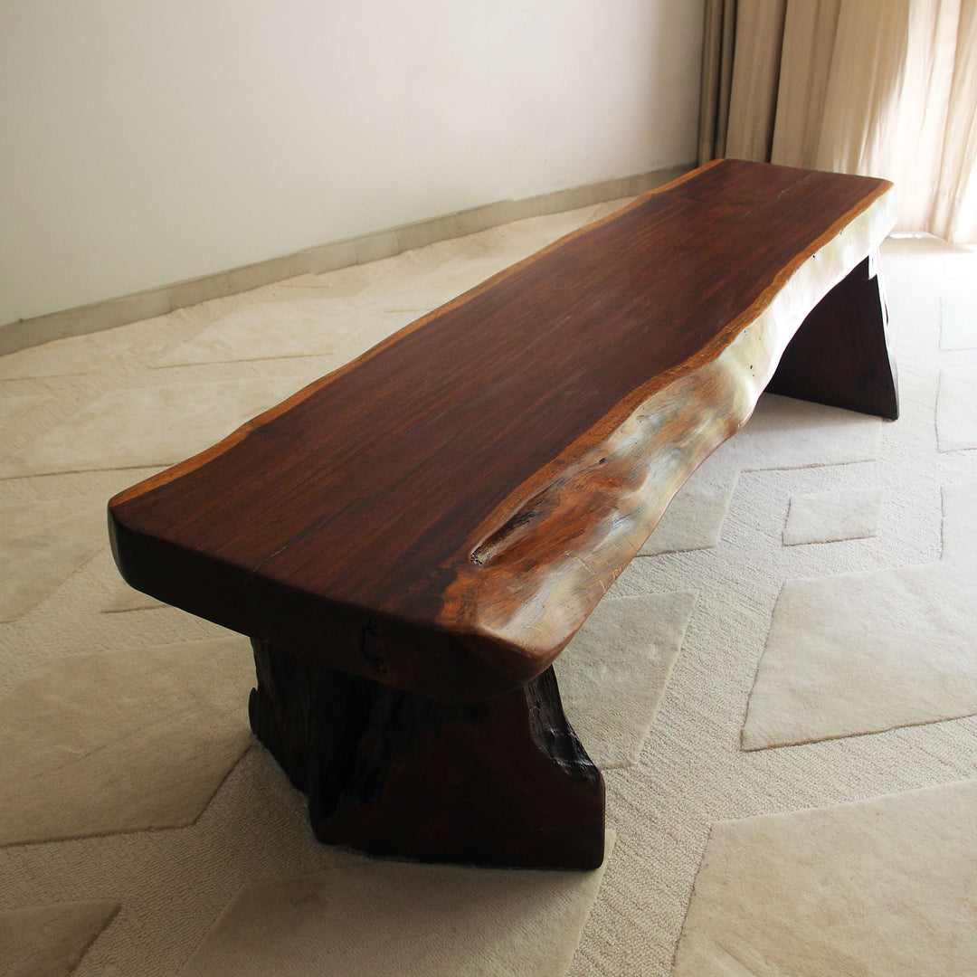 Wooden bench with a natural edge design on a tiled floor.