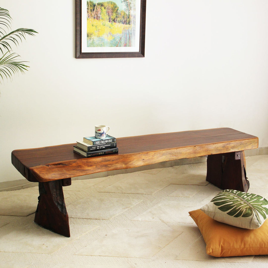 Wooden bench in a room with a painting on the wall and a plant.