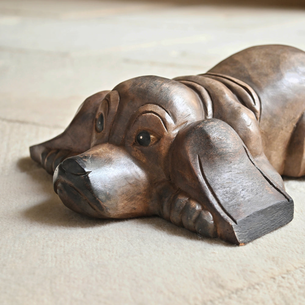 Close-up of the wooden dog’s face, spread ears and carved eyes.