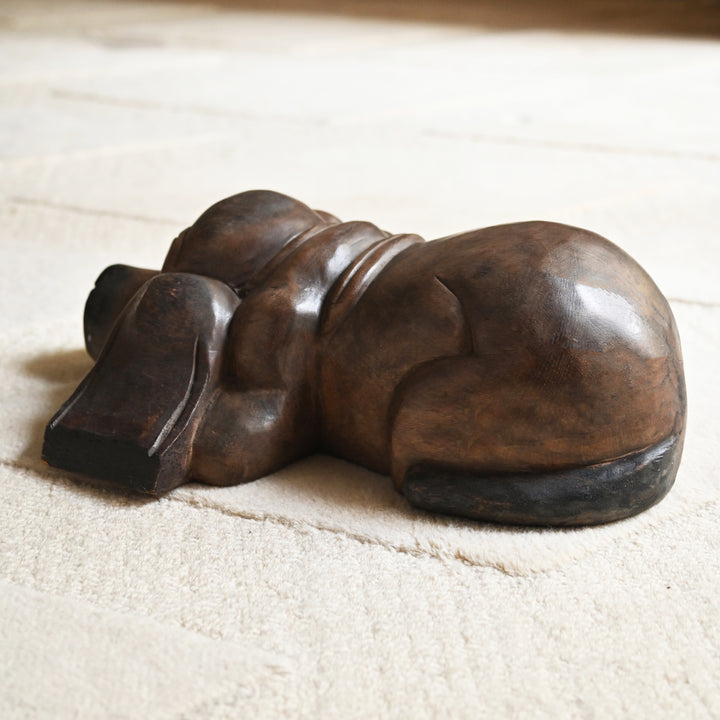 Rear view of the carved wooden dog showing its rounded back and curled tail.