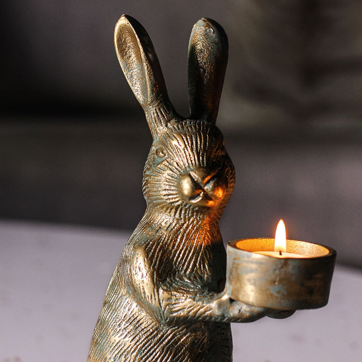 Close-up of the antique gold rabbit candle holder holding a lit tealight