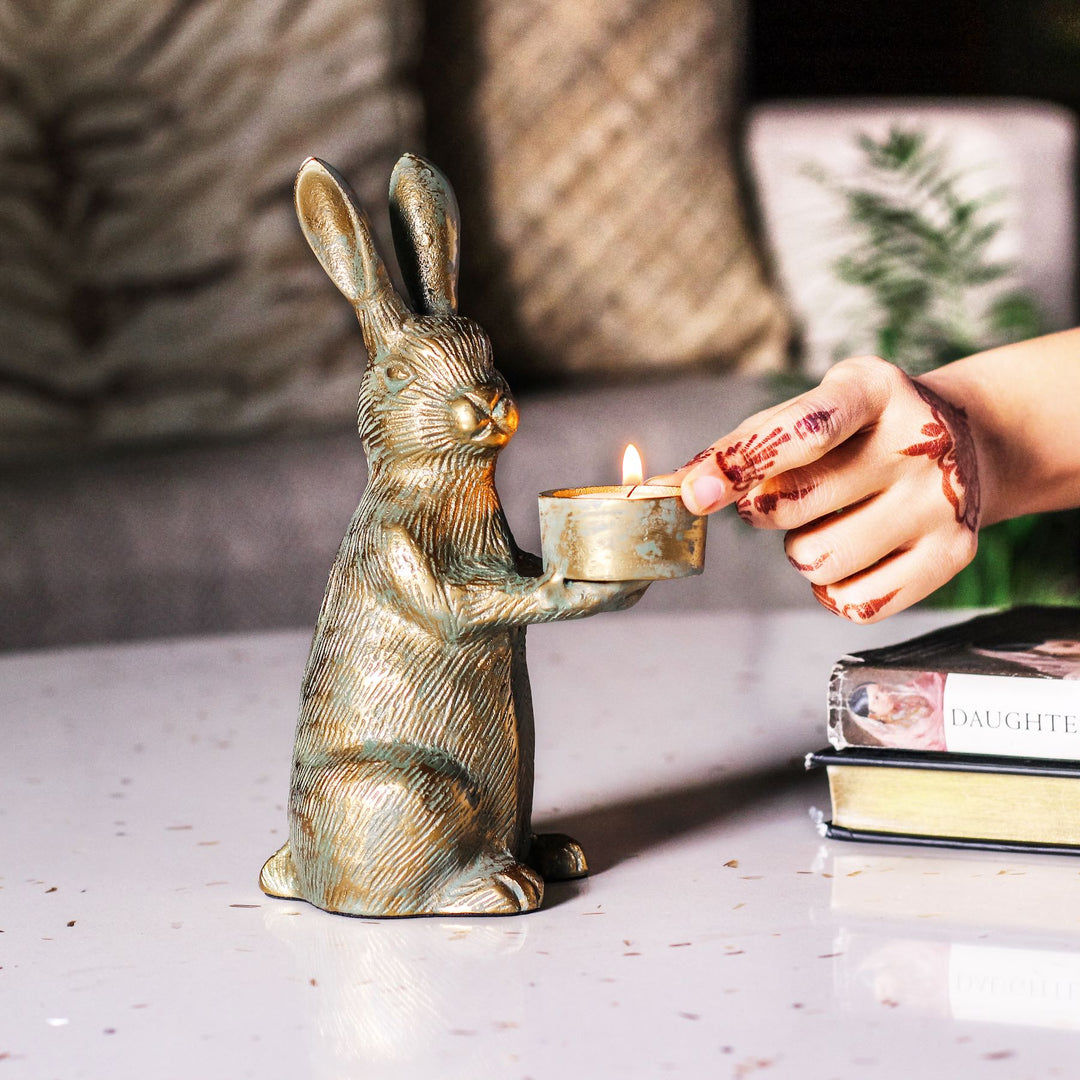 Hand lighting a tealight held by the antique gold rabbit candle holder