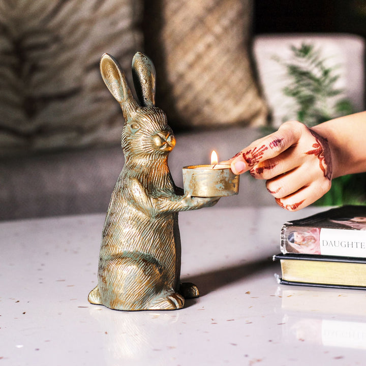Hand lighting a tealight held by the antique gold rabbit candle holder