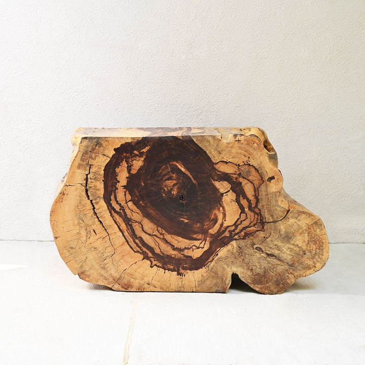 A sliced and carved teak flat console table displayed vertically with decorative items on top against a plain background