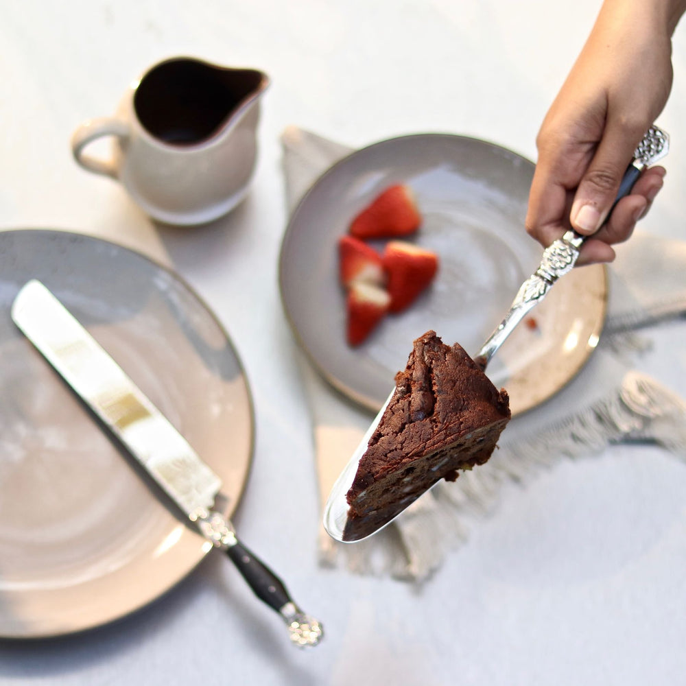 A hand using the Windsor cake server to lift a slice of chocolate cake.