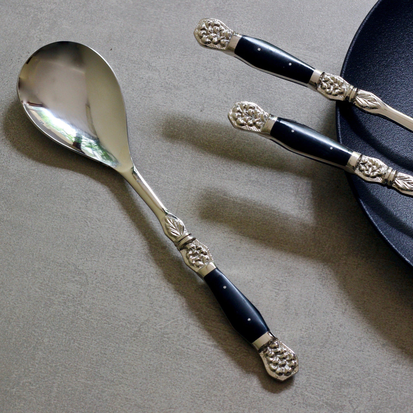 stainless steel serving spoon with black inlay handles